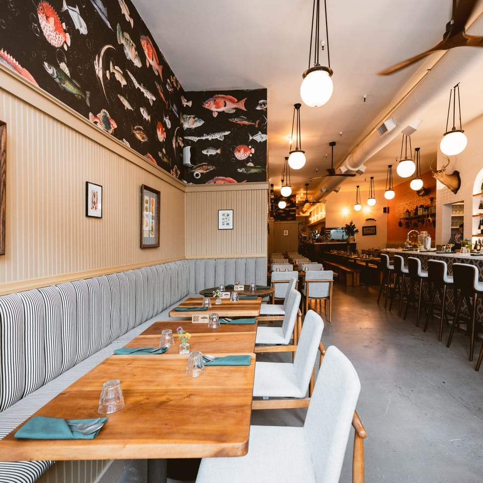 Teakwood Thai Chophouse dining room with banquette seating, wooden tables, and a fish-patterned accent wall.