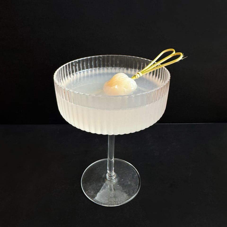 A Teakwood Thai Chophouse cocktail in a ribbed glass, garnished with a lychee and lemongrass.